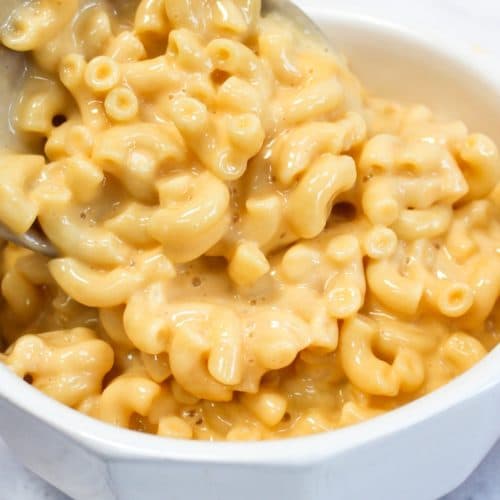 one-pot stove top mac and cheese put into a white bowl from a wooden spoon