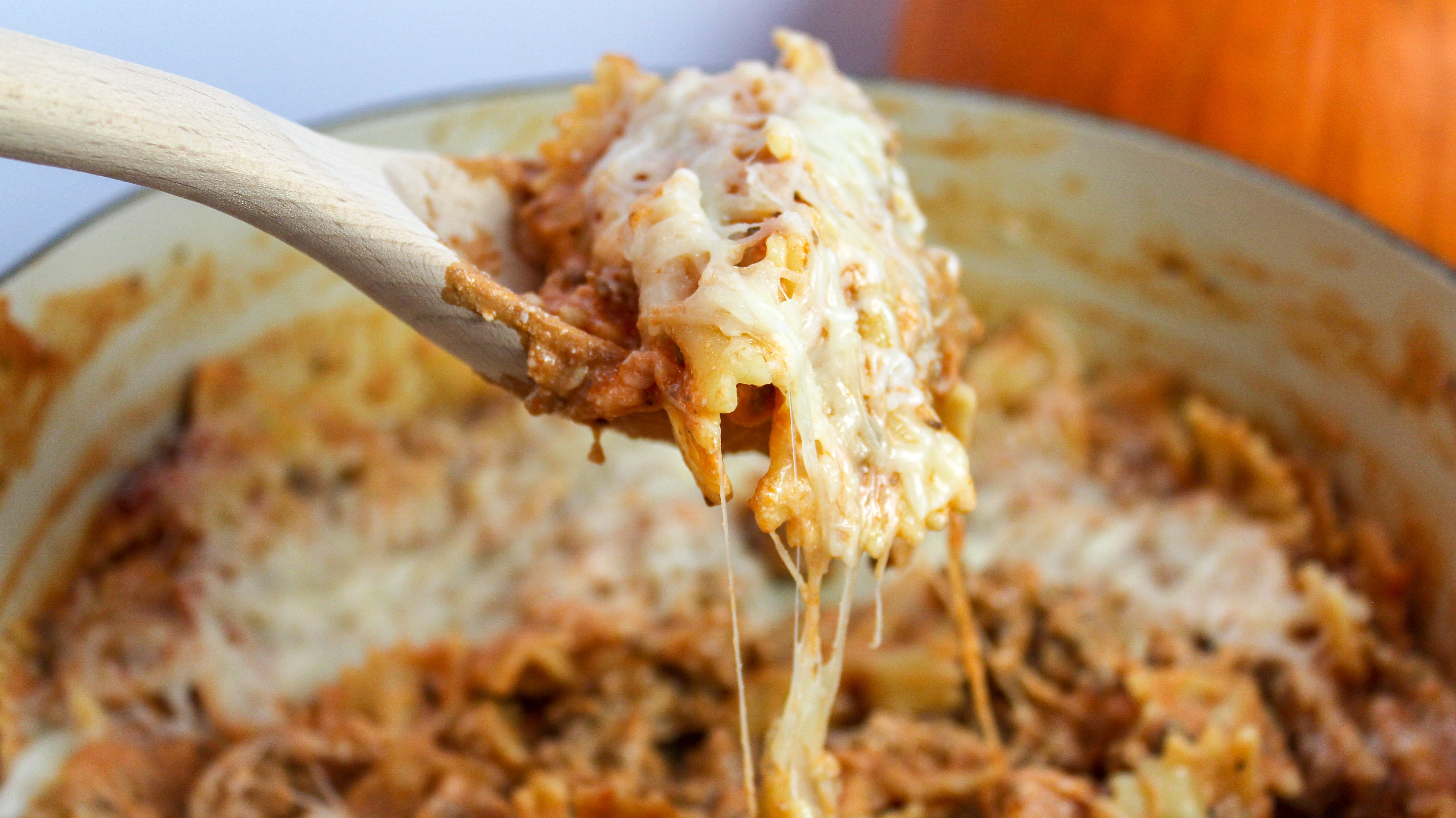pasta scooped with a wooden spoon from a red pot
