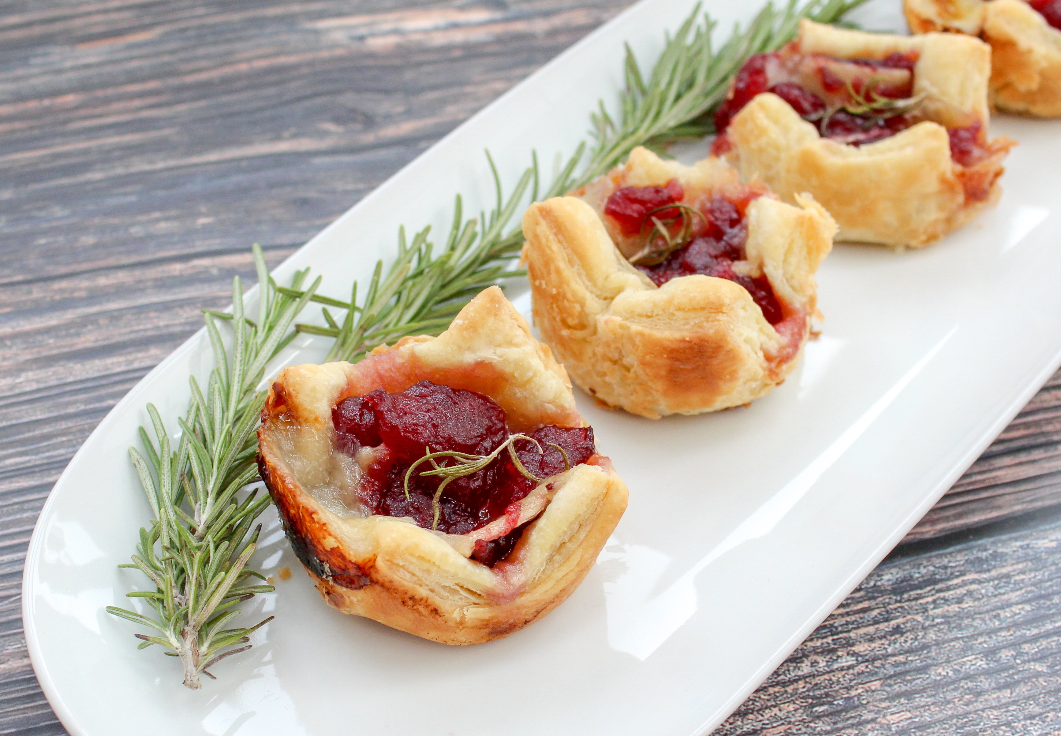 Cranberry and brie cheese in baked puffed pastry topped with rosemary