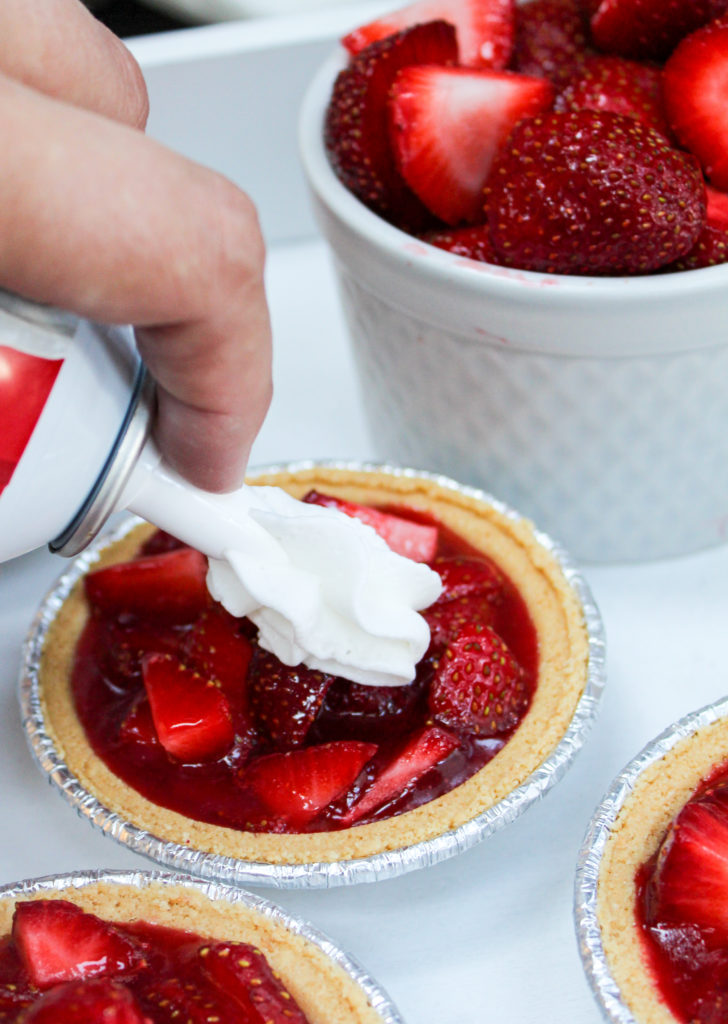 mini strawberry pies on a platter with whipped cream