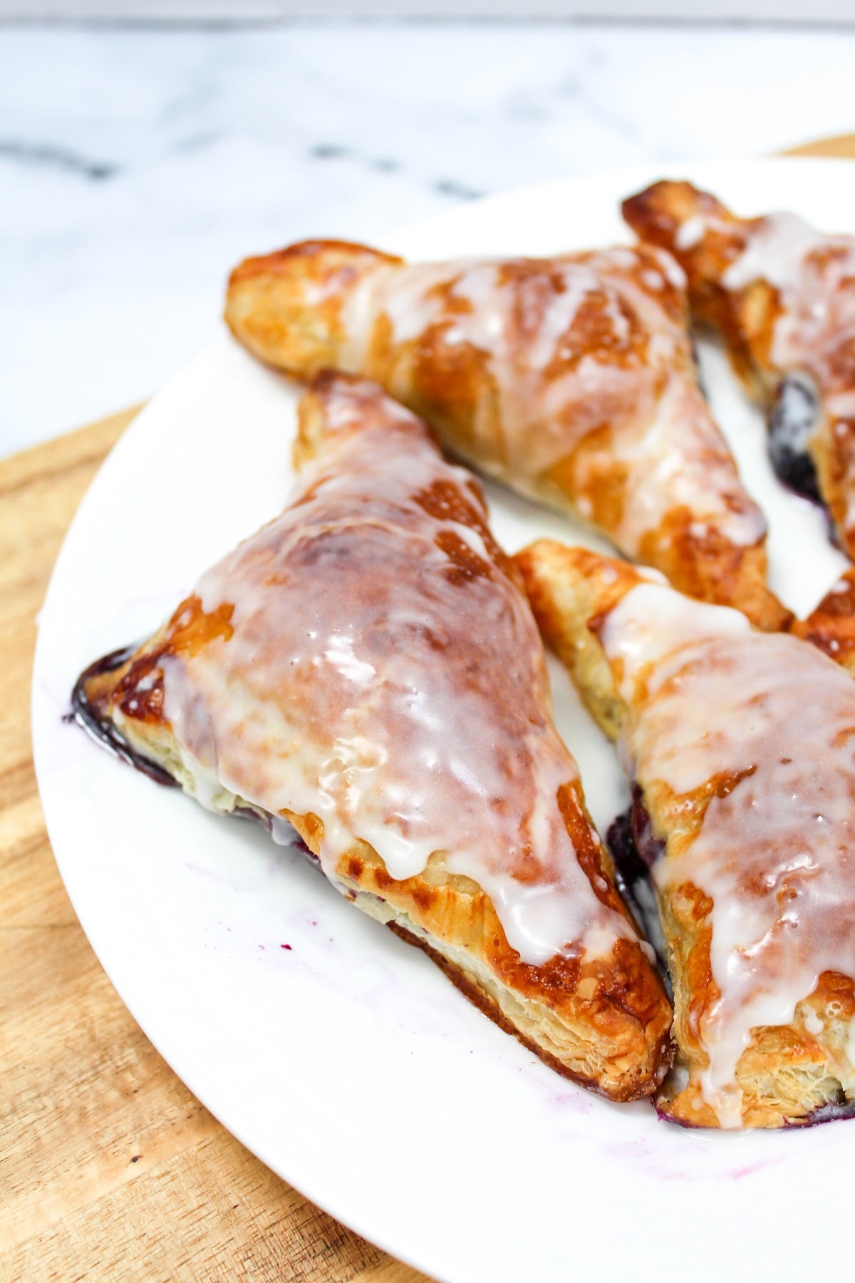 cooked blueberry turnover with frosting on a white plate
