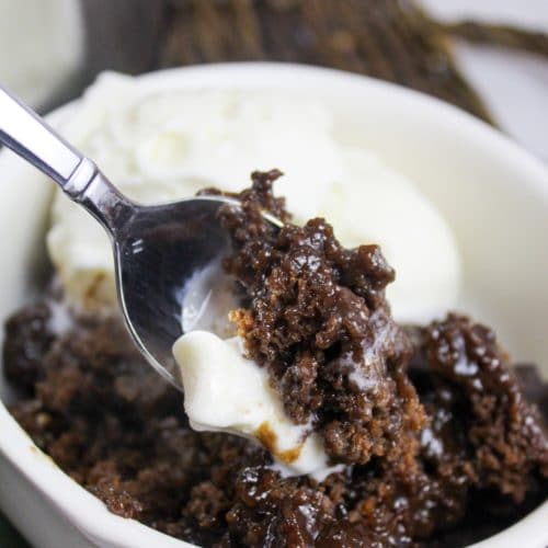 slow cooker chocolate cobbler in a bowl with vanilla ice cream with spoon