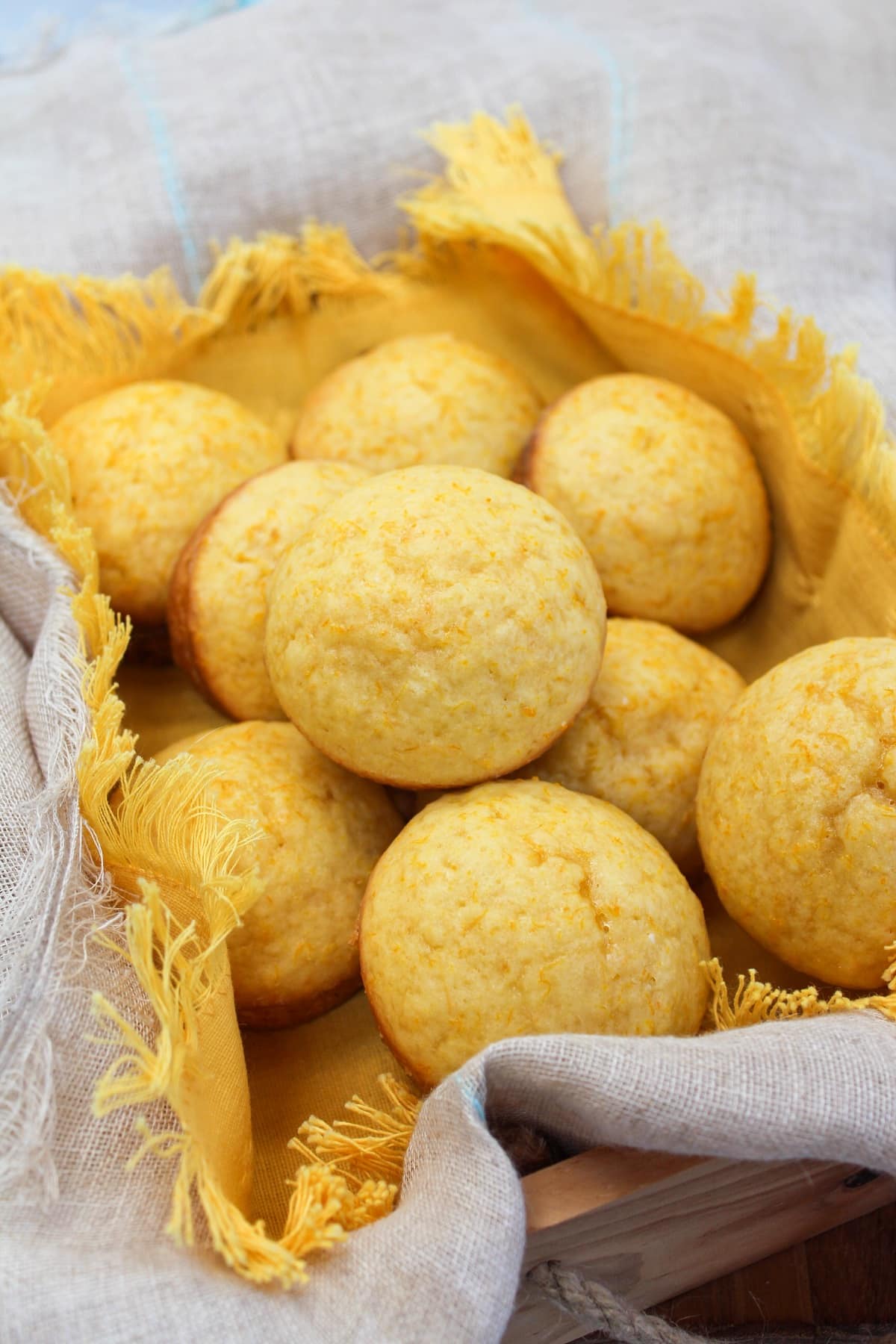 Muffins in a basket with a yellow cloth. Muffins are stacked on each other.