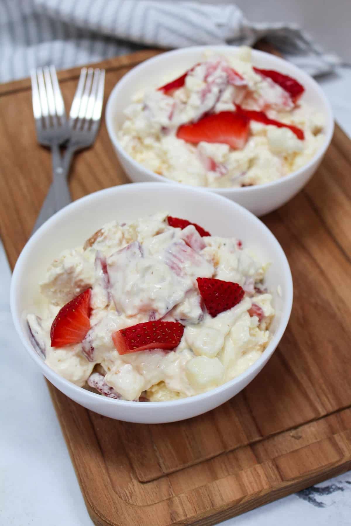 dessert conntaining strawberries, pudding, whipped topping, and angel food cake mixed together in a white bowl.