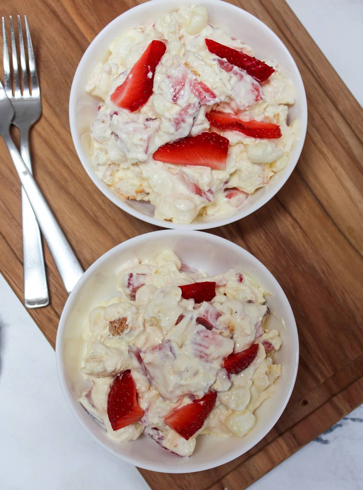 dessert conntaining strawberries, pudding, whipped topping, and angel food cake mixed together in a white bowl.